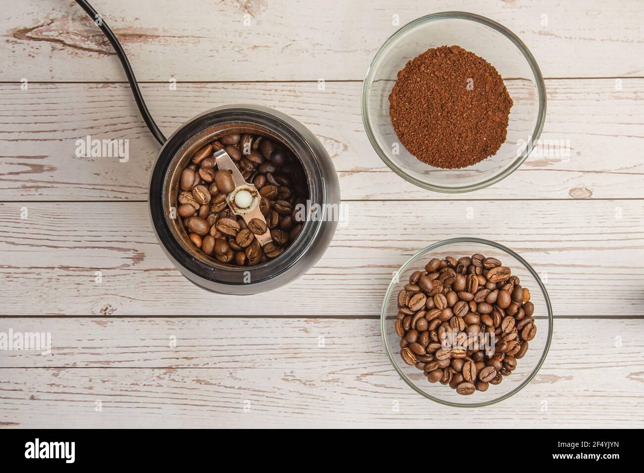 Kaffeebohnen in der Mühle und gemahlener Kaffee in der Schüssel auf dem Holzhintergrund Draufsicht Stockfoto