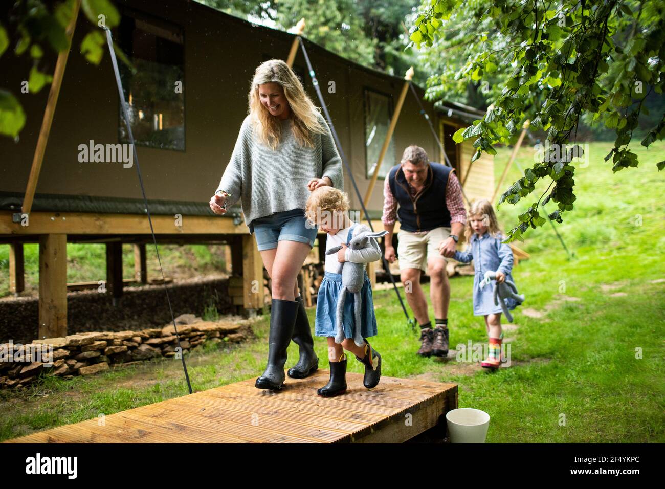 Glückliche Familie, die Hände hält, die draußen in der Hütte im Wald spazieren gehen Stockfoto
