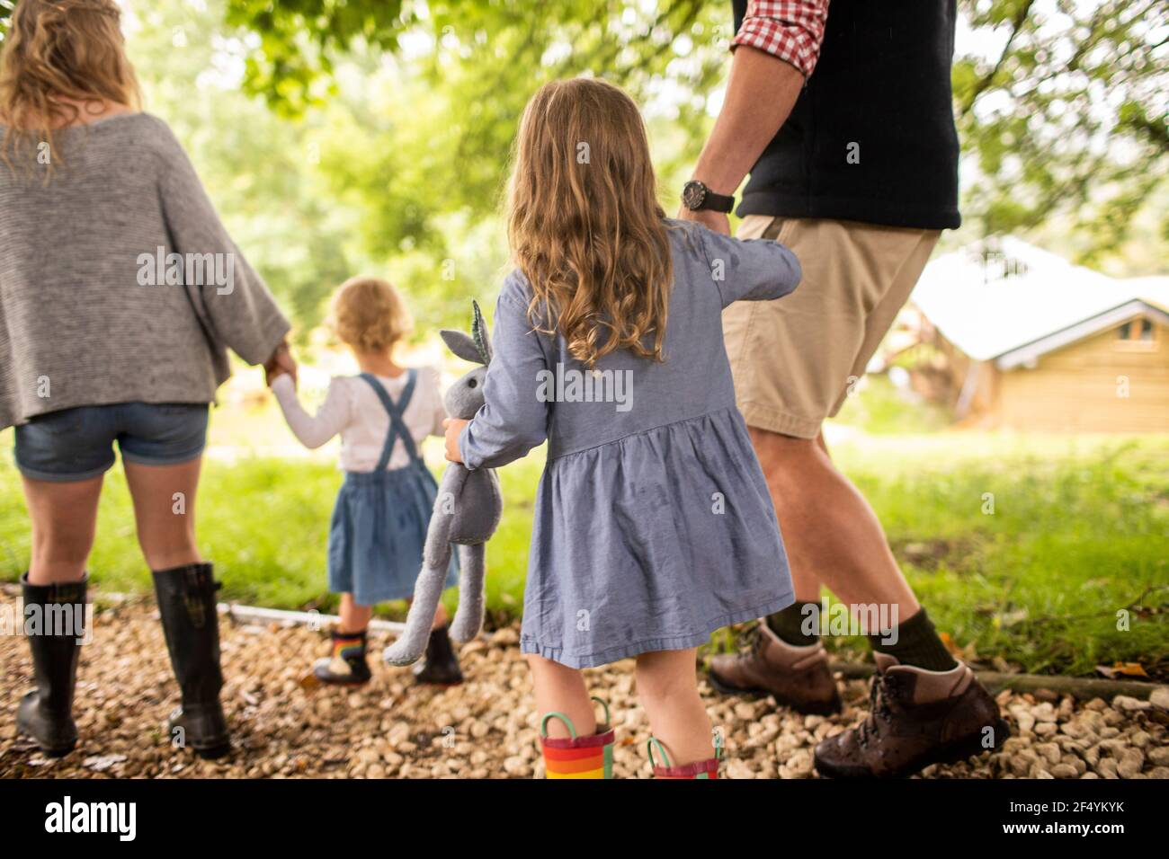 Nettes Mädchen mit ausgestopften Tier hält Hände mit Vater auf Pfad Stockfoto