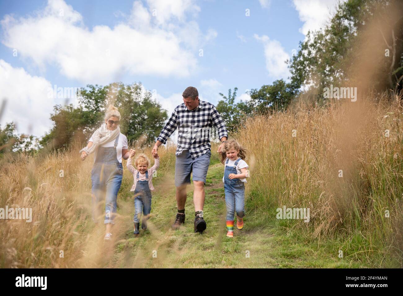 Glückliche Familie hält Hände laufen in sonnigen ländlichen Feld Stockfoto