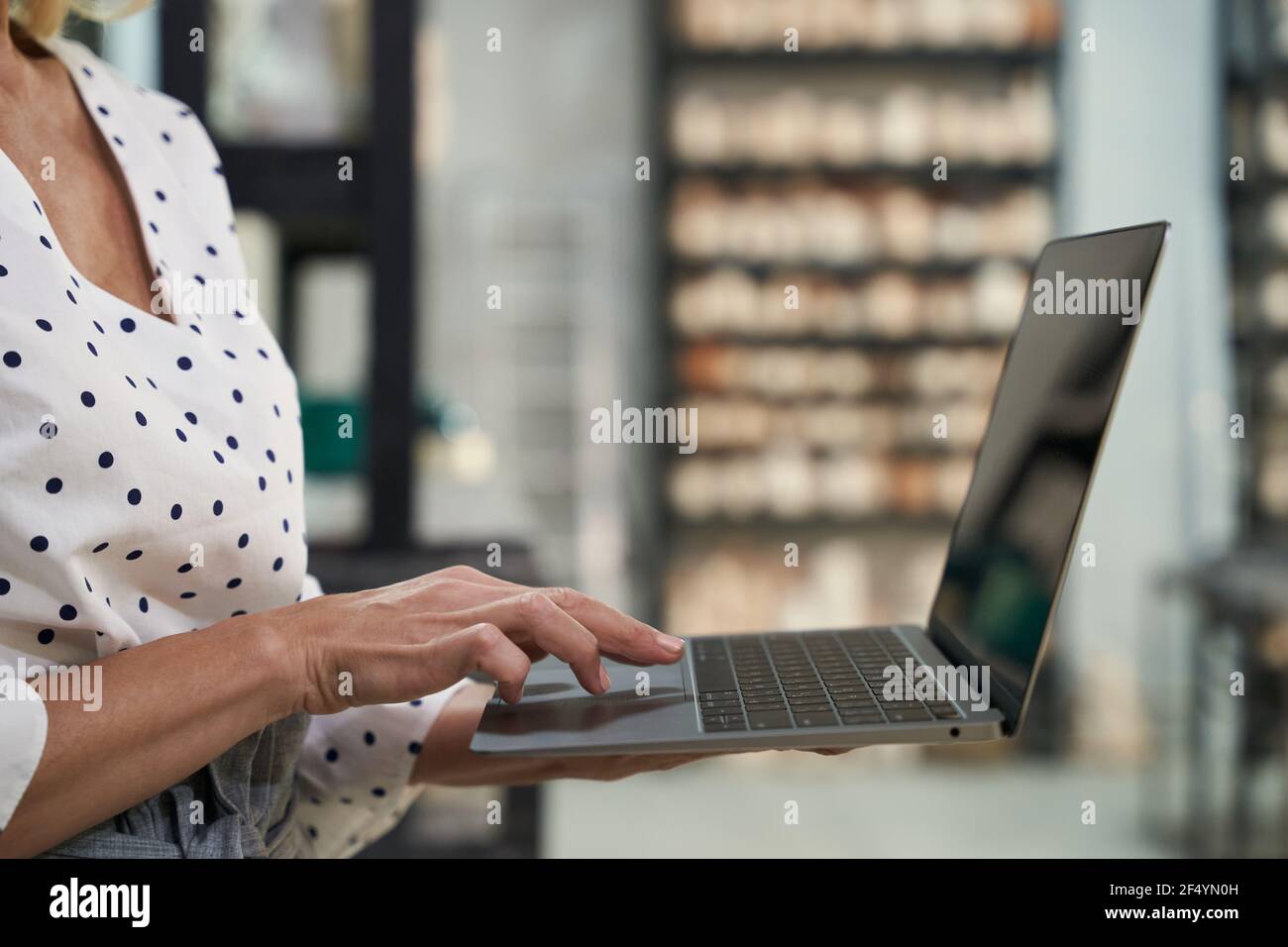 Nahaufnahme der Hände von reifen Geschäftsfrau arbeiten an Der Laptop, während sie in ihrem Töpferwarenladen stand Stockfoto