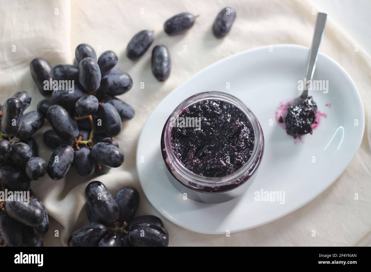 Hausgemachte Traubenmarmelade mit drei Zutaten, kernlosen schwarzen Trauben, Zucker und Limettensaft. Aufnahme auf weißem Hintergrund Stockfoto