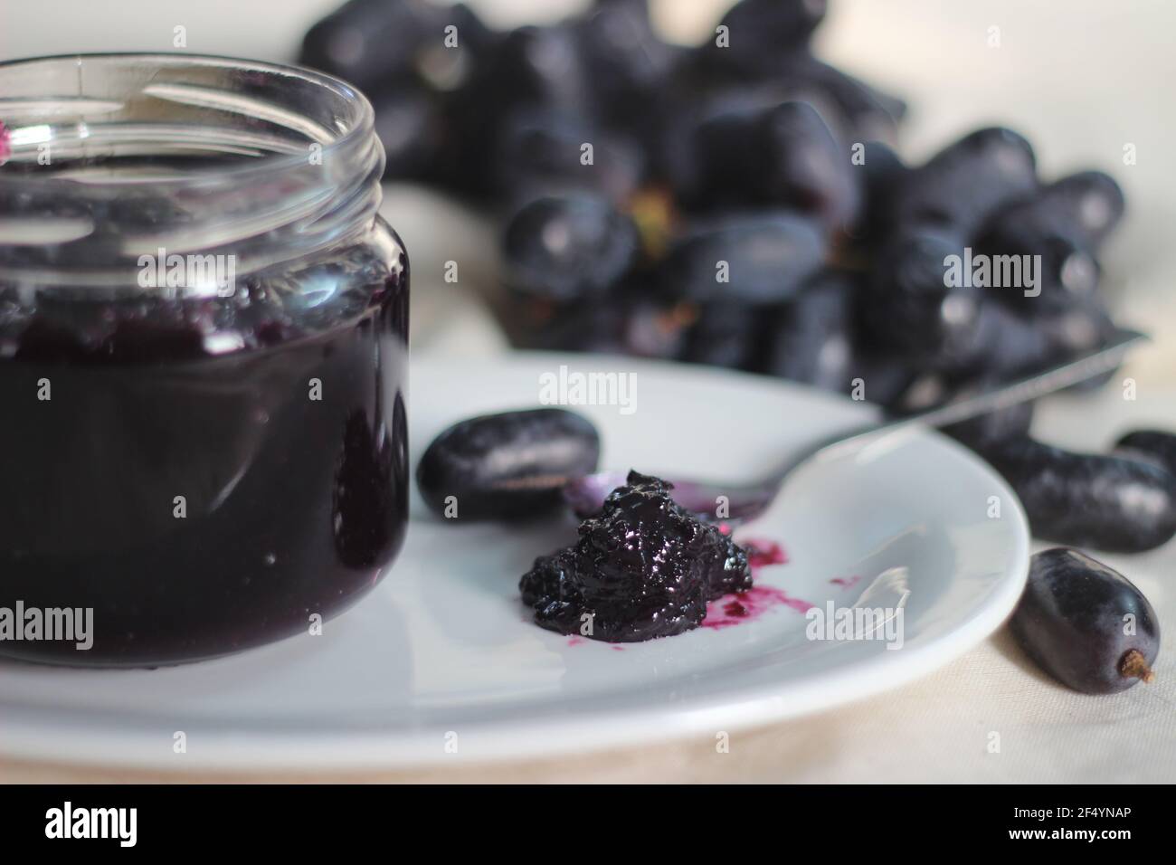 Hausgemachte Traubenmarmelade mit drei Zutaten, kernlosen schwarzen Trauben, Zucker und Limettensaft. Aufnahme auf weißem Hintergrund Stockfoto