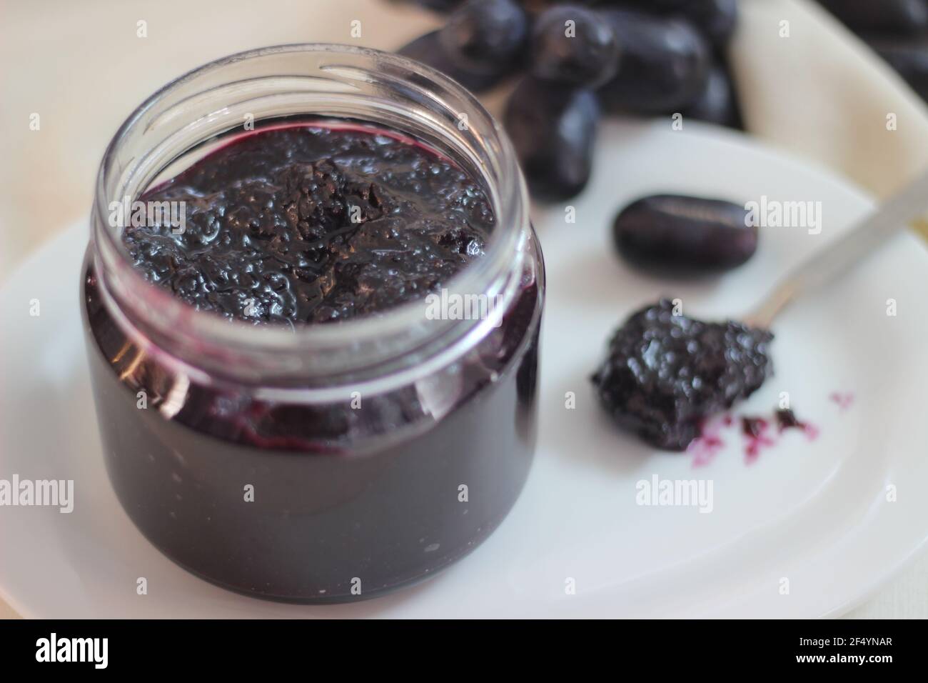 Hausgemachte Traubenmarmelade mit drei Zutaten, kernlosen schwarzen Trauben, Zucker und Limettensaft. Aufnahme auf weißem Hintergrund Stockfoto