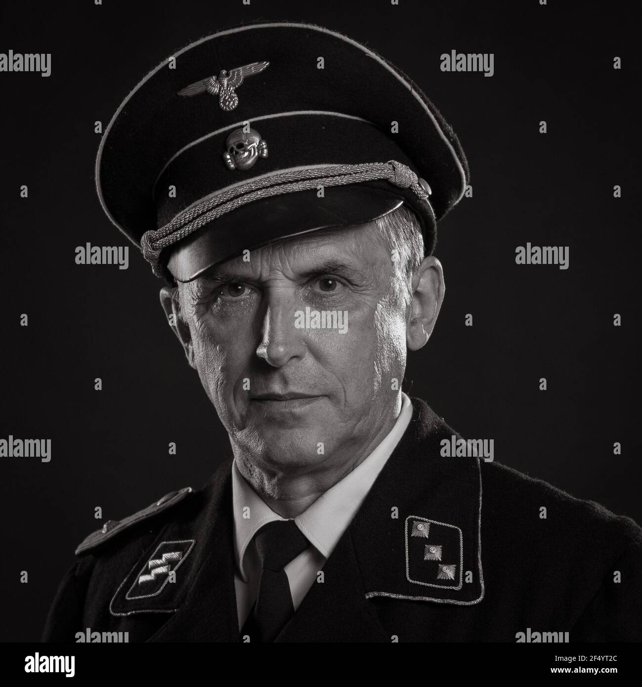Mann Schauspieler in historischer Militäruniform als Offizier der deutschen Armee während des Zweiten Weltkriegs, posiert auf einem schwarzen Hintergrund in einem blauen szenischen Licht Stockfoto