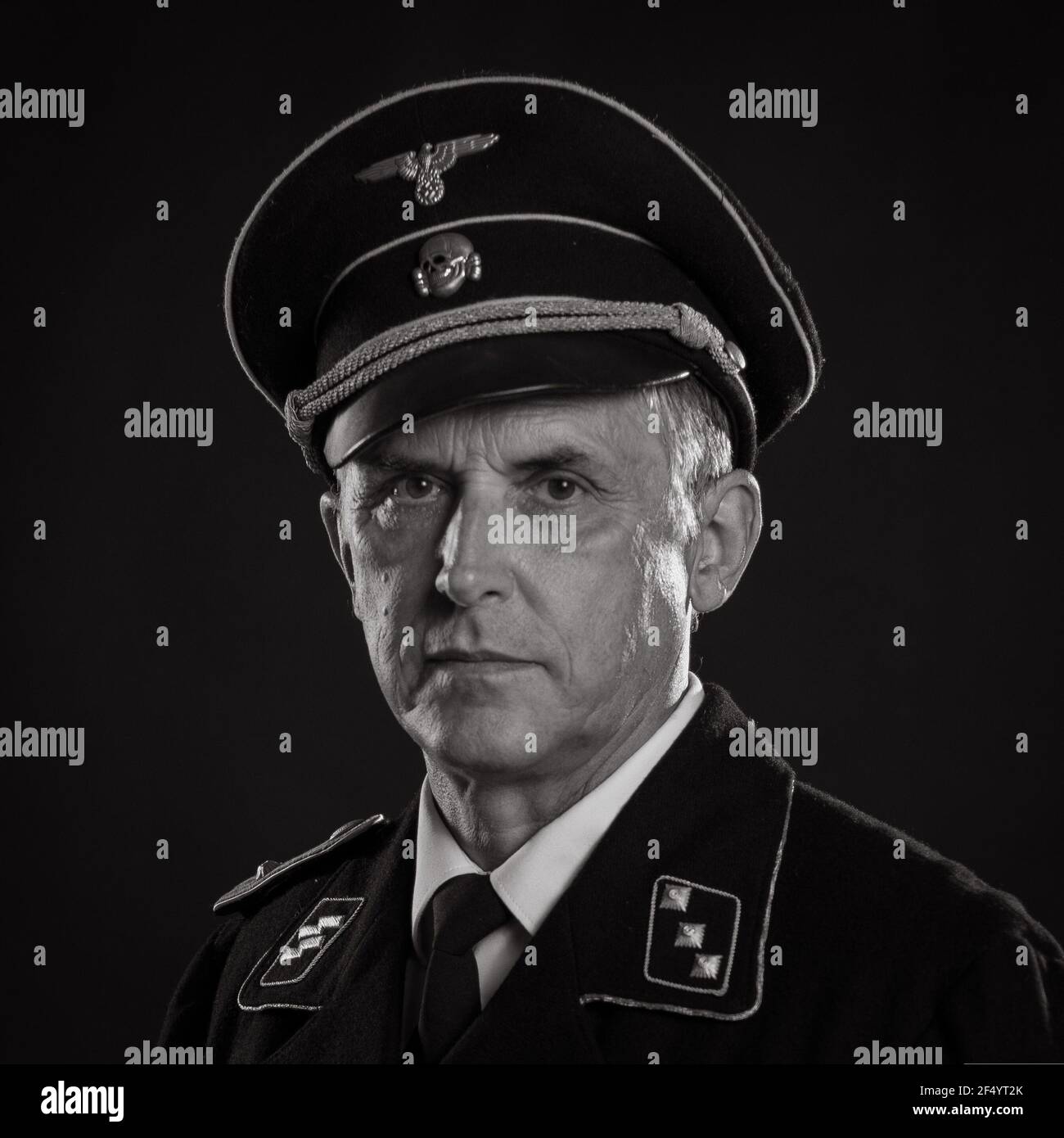 Mann Schauspieler in historischer Militäruniform als Offizier der deutschen Armee während des Zweiten Weltkriegs, posiert auf einem schwarzen Hintergrund in einem blauen szenischen Licht Stockfoto