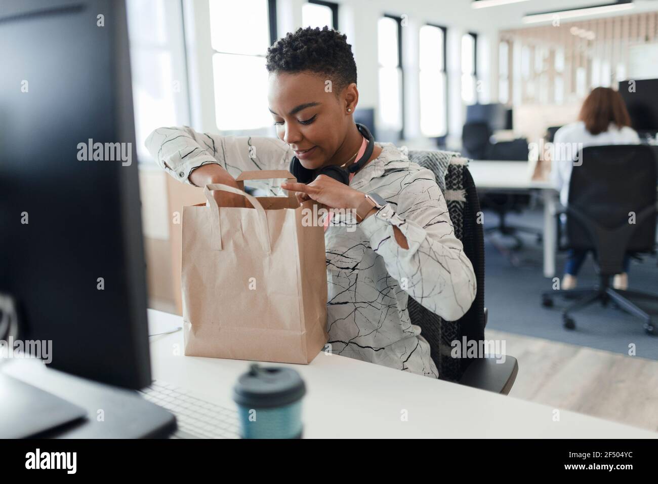 Geschäftsfrau öffnet Mittagstasche an der Rezeption im Büro Stockfoto