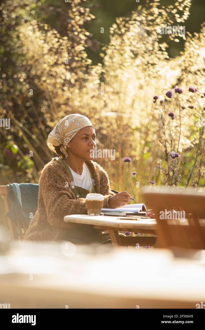 Frau mit Kaffee arbeitet am sonnigen Gartentisch Stockfoto