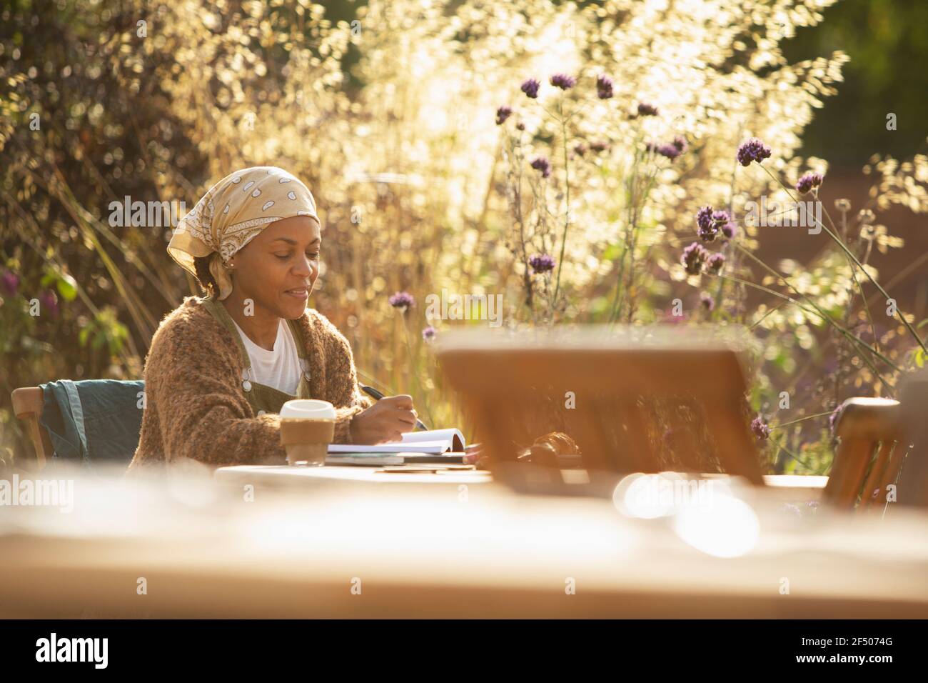 Frau, die am Kaffeetisch im sonnigen Garten arbeitet Stockfoto