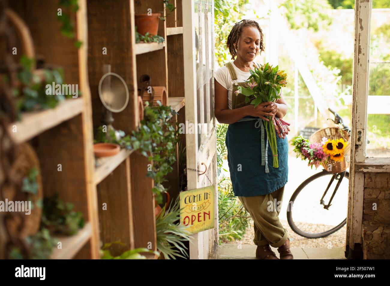 Weibliche Floristin hält Blumenstrauß in Shop Eingang Stockfoto