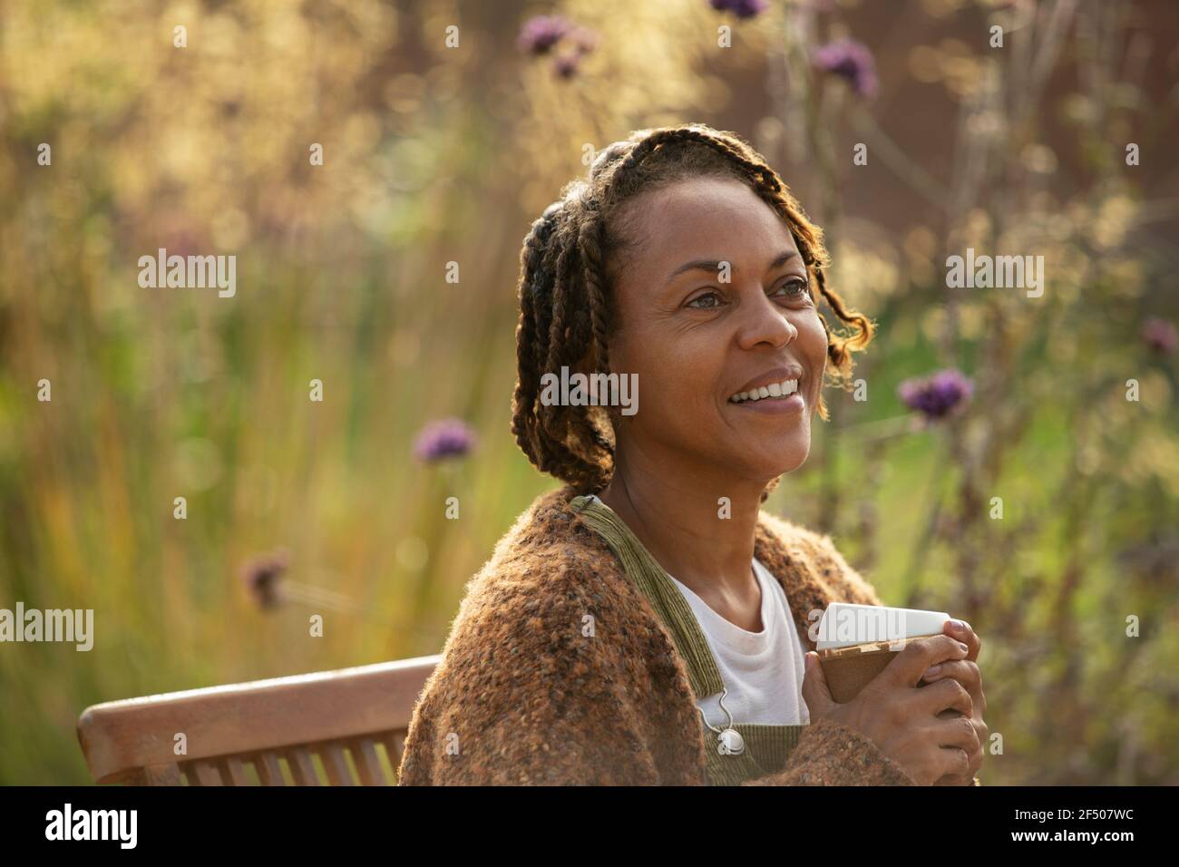 Glückliche Frau, die Kaffee im sonnigen Garten genießt Stockfoto
