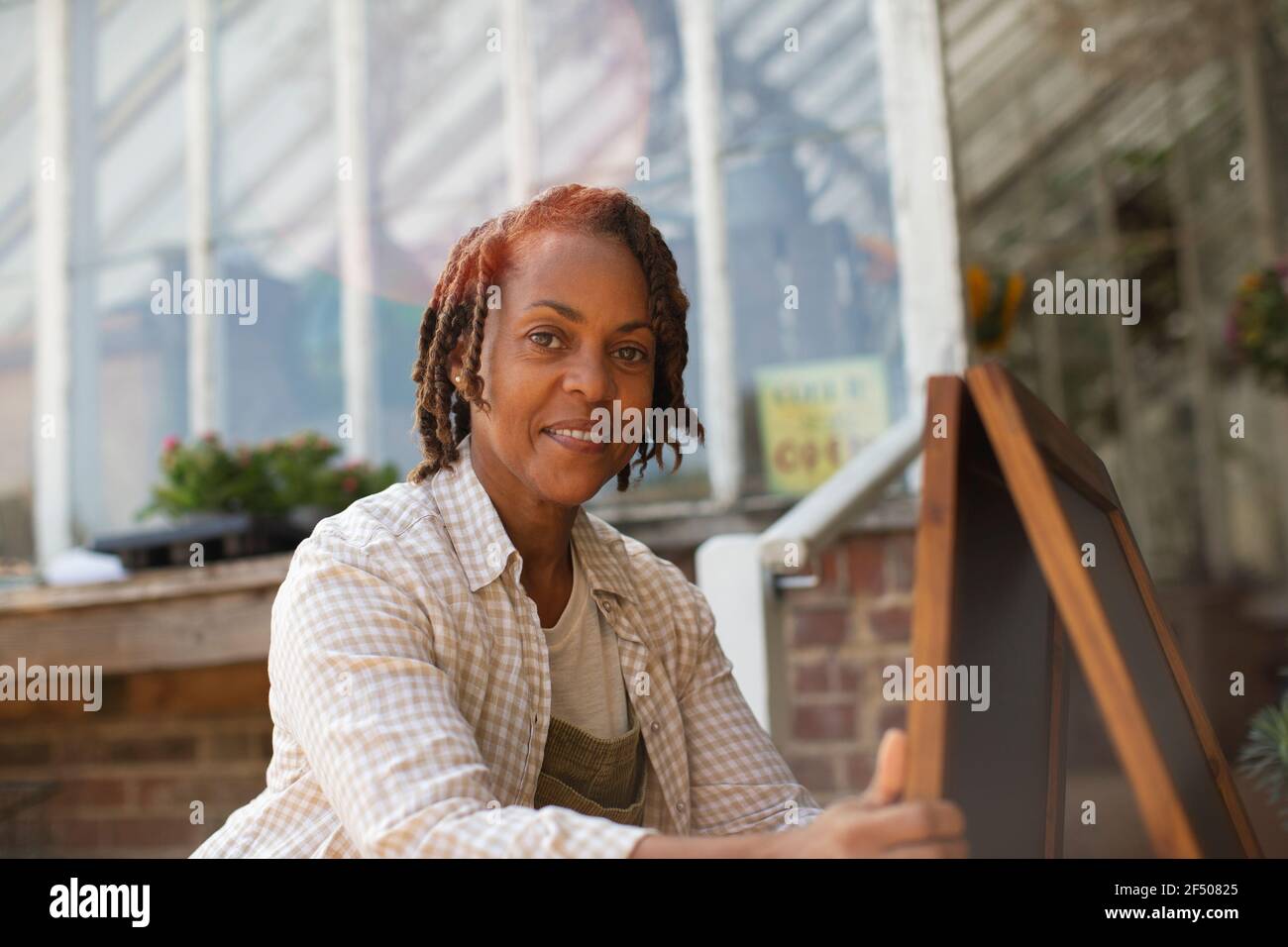 Portrait selbstbewusste weibliche Pflanzenzügnerei Besitzerin mit Schild Stockfoto