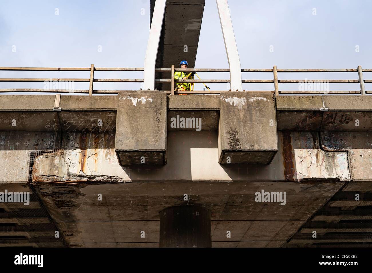 Glasgow, Schottland, Großbritannien. 23. März 2021. Glasgow, Schottland, Großbritannien. Ein Ingenieur auf dem Viadukt bei Fahrbahnsperrungen auf dem M8 prüft die bauliche Integrität des Betonviadukts. Das Foto zeigt schwere Betonabplatzungen und Korrosion von Stahlarmierungsstäben an den Halb-Fugen, wo der Brückenüberbau vom Pier gestützt wird. Alle Brückenpfeilern und Halbverbindungen wurden für Abhilfemaßnahmen und Reparaturen markiert, die längere Fahrbahnsperrungen erfordern.Iain Masterton/Alamy Live News Stockfoto