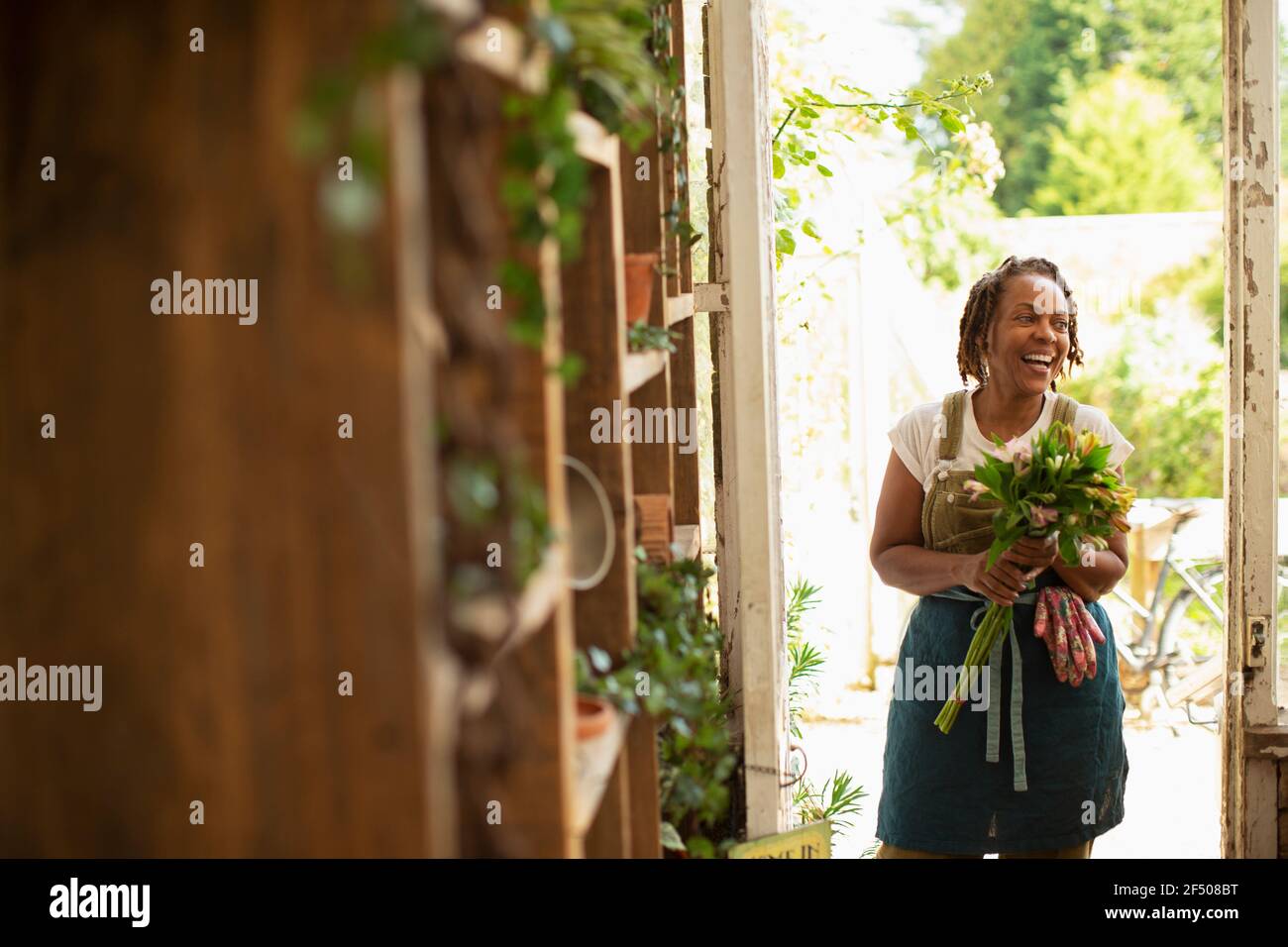 Glückliche weibliche Floristin mit Blumenstrauß in Shop Eingang Stockfoto