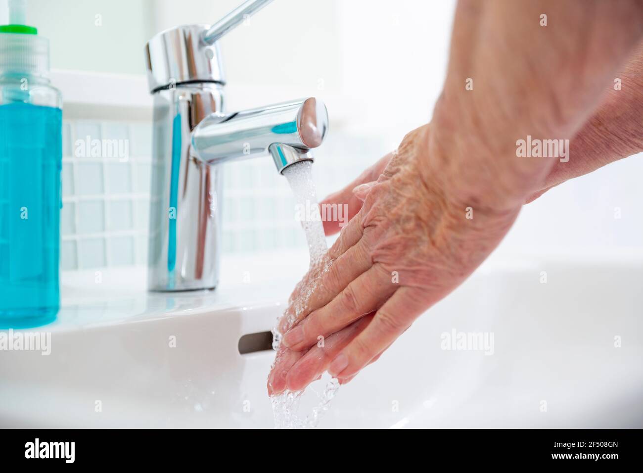 Nahaufnahme ältere Frau, die sich am Waschbecken im Bad die Hände wascht Stockfoto