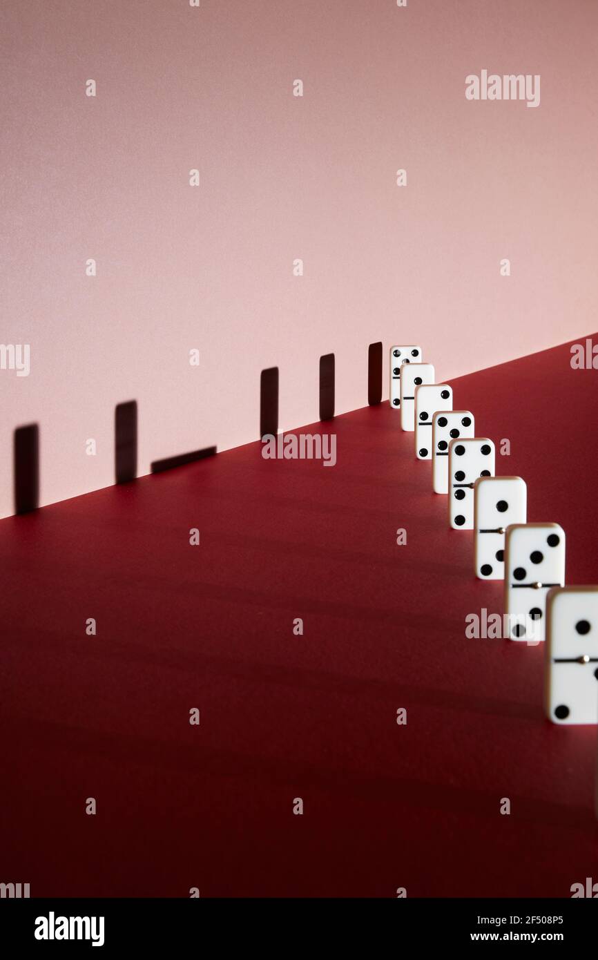 Gefallener Dominoschatten auf rotem Hintergrund Stockfoto
