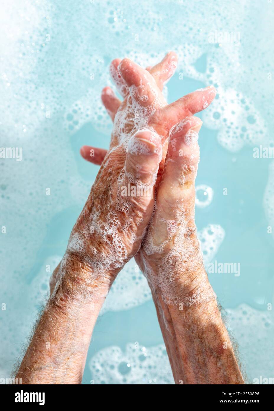 Nahaufnahme einer älteren Frau, die sich in Seifenwasser die Hände wäscht Stockfoto