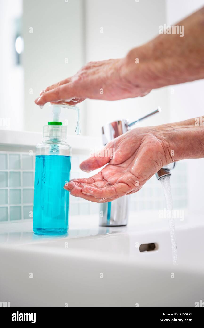 Ältere Frau, die sich im Waschbecken Hände mit Seife wascht Stockfoto