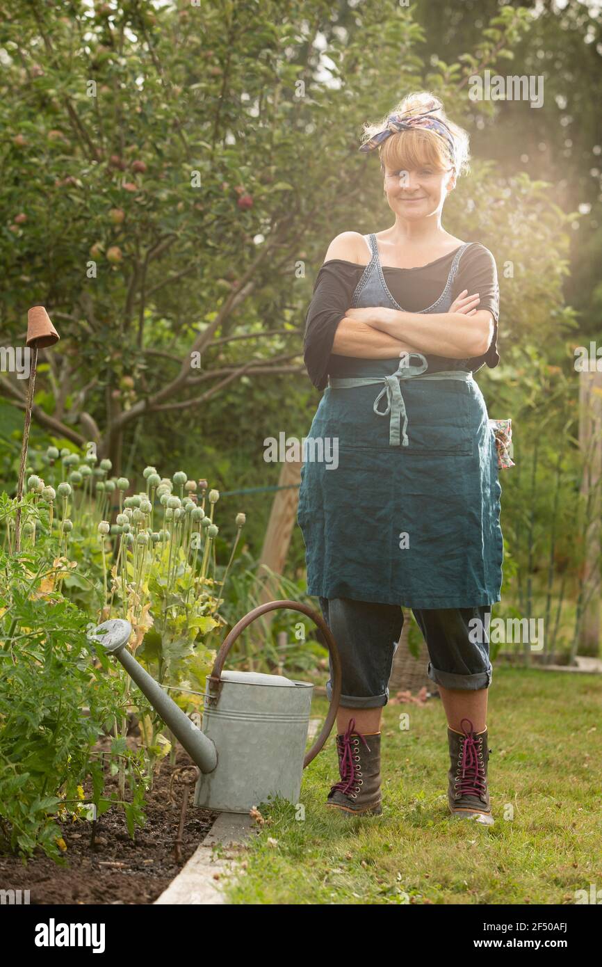 Portrait selbstbewusste Frau mit Gießkanne im Sommergarten Stockfoto