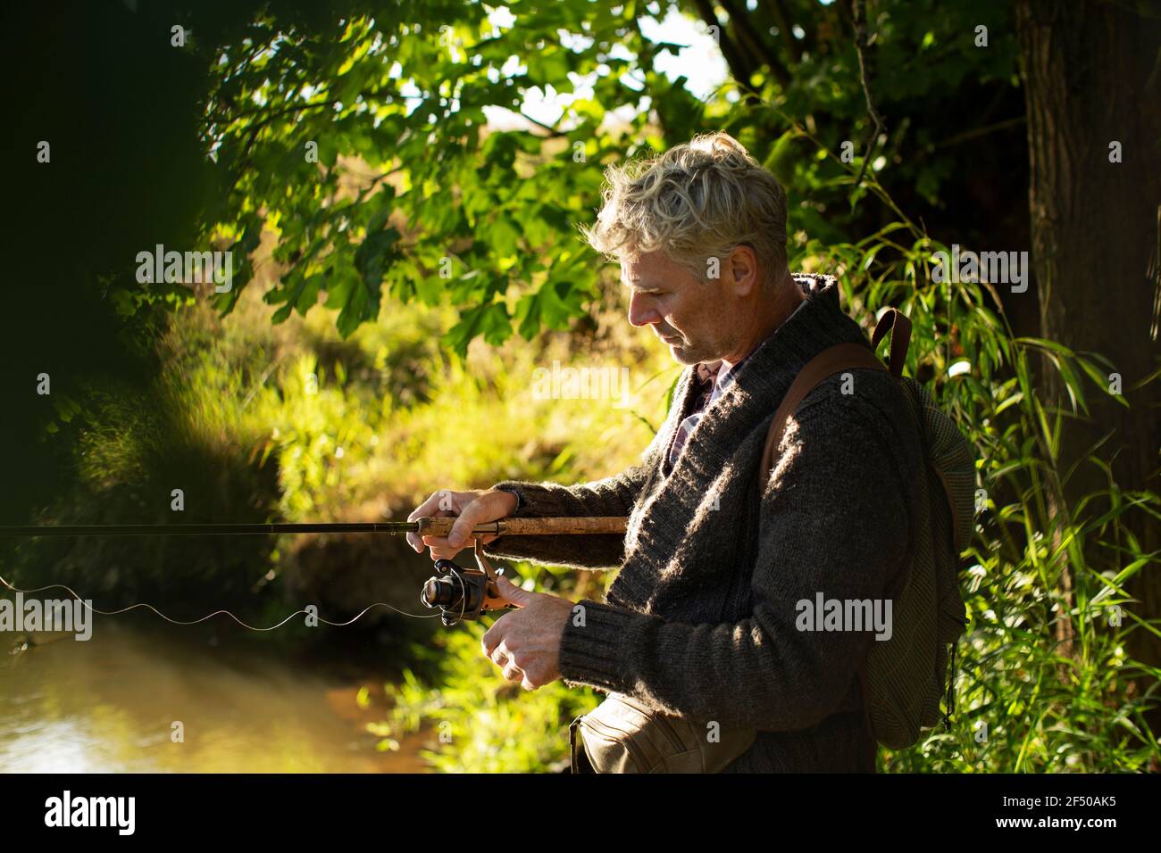 Mann, der Fliegenfischen Linie am sonnigen Flussufer vorbereitet Stockfoto