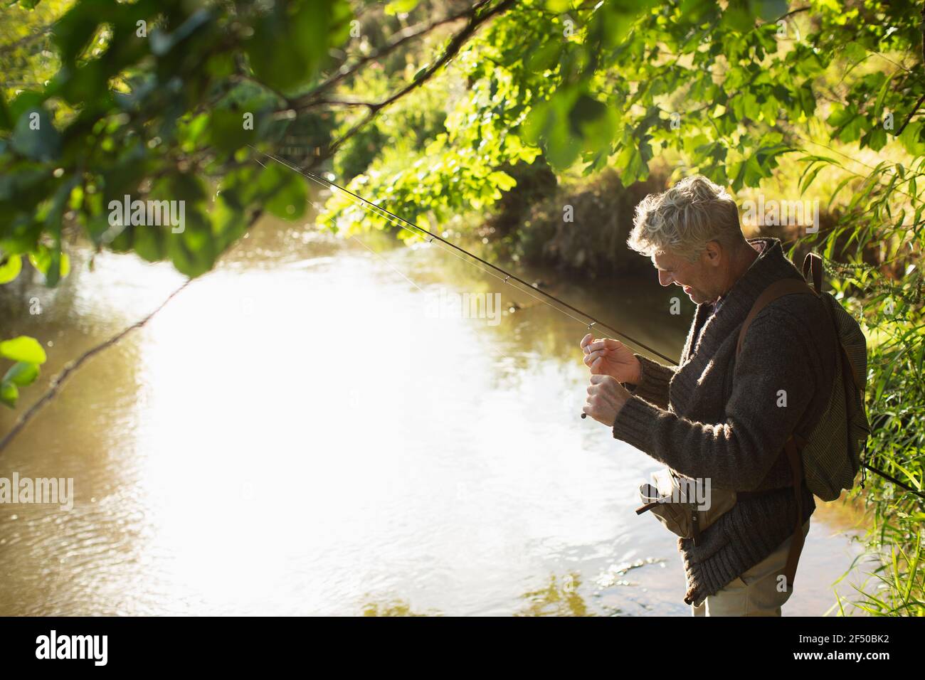 Mann, der Fliegenfischen Linie am sonnigen Flussufer vorbereitet Stockfoto