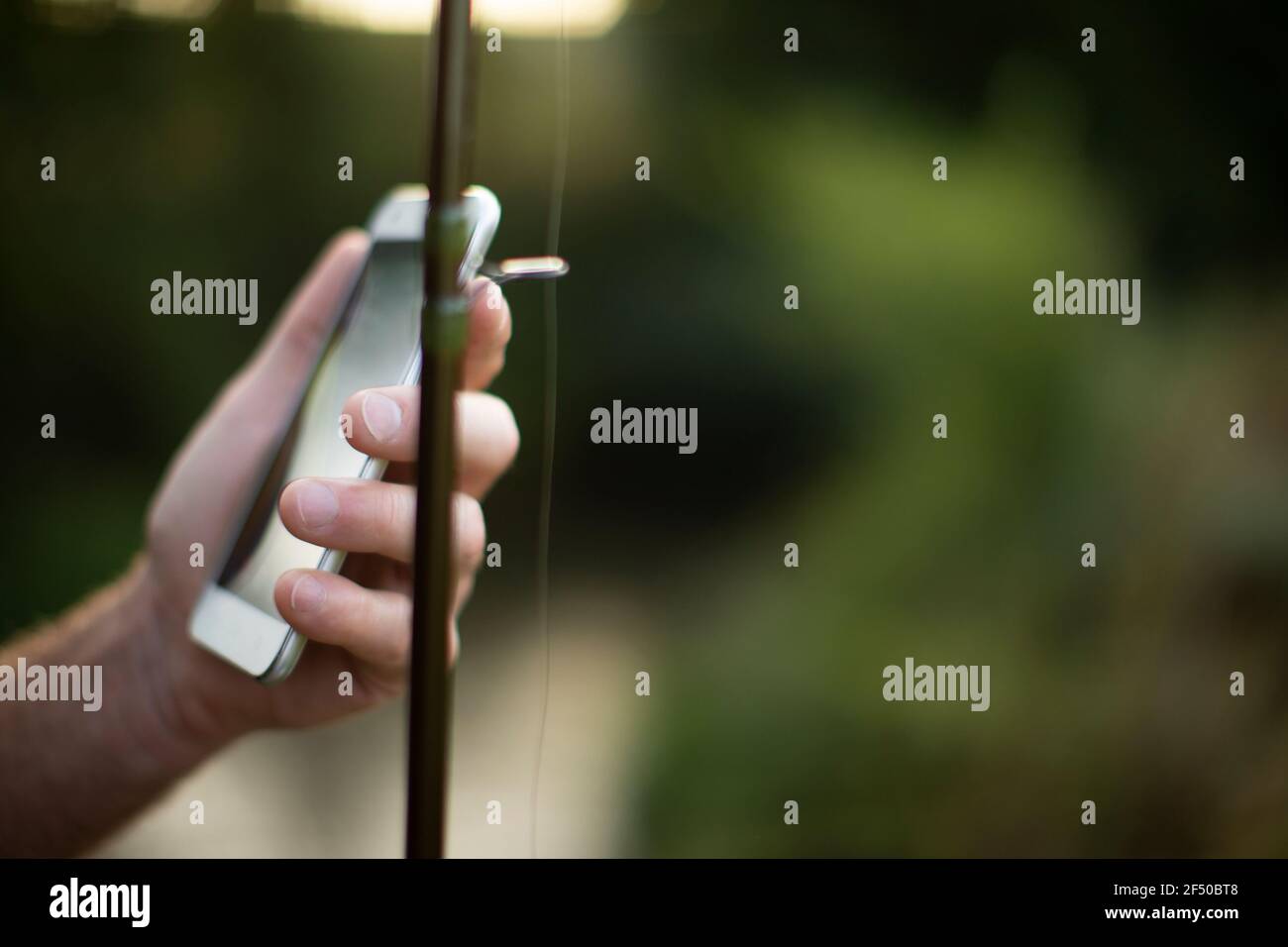 Nahaufnahme Hand hält Smartphone und Angelrute Stockfoto
