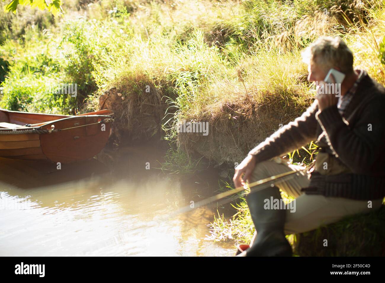 Mann Fliegenfischen und im Gespräch auf Smartphone bei sonnig Fluss Stockfoto