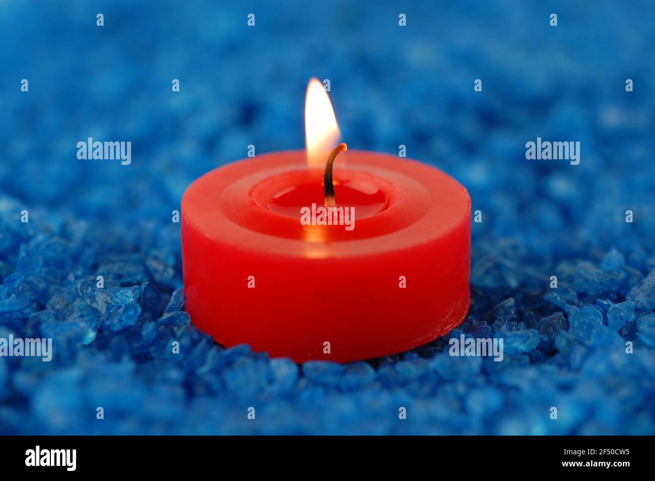 Rote Kerze auf dem blauen Meersalz für Spa. Konzentrieren Sie sich auf einen Docht. Stockfoto