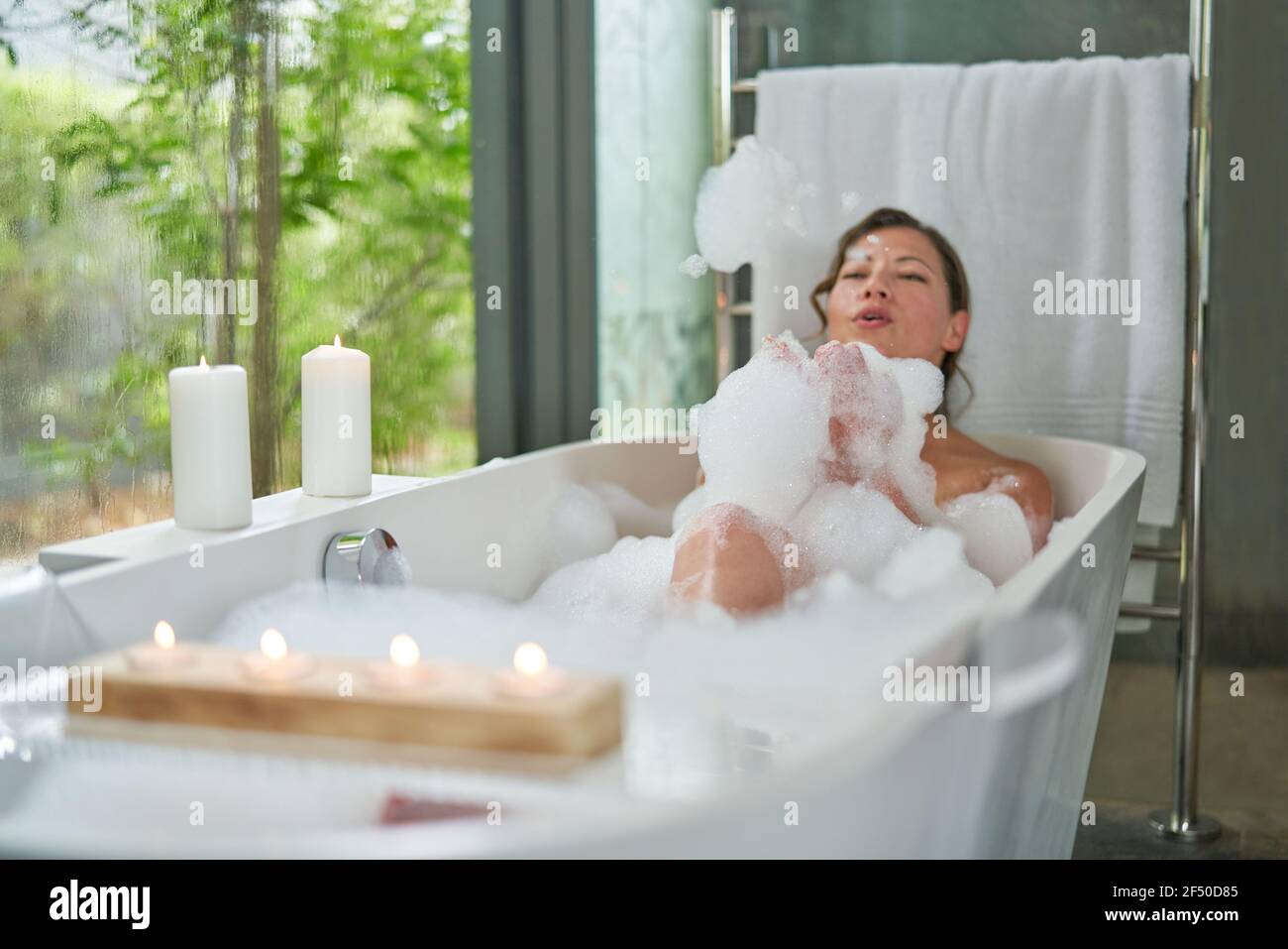 Verspielte Frau im Schaumbad in der modernen Badewanne Stockfoto
