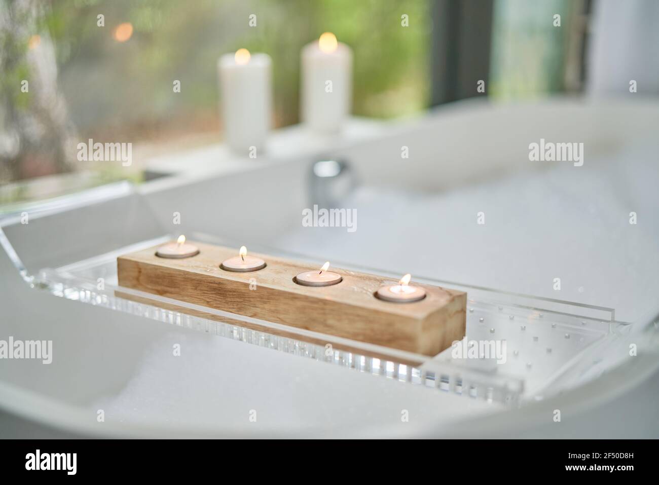 Teelicht Kerzen auf Tablett über Schaumbad Stockfoto