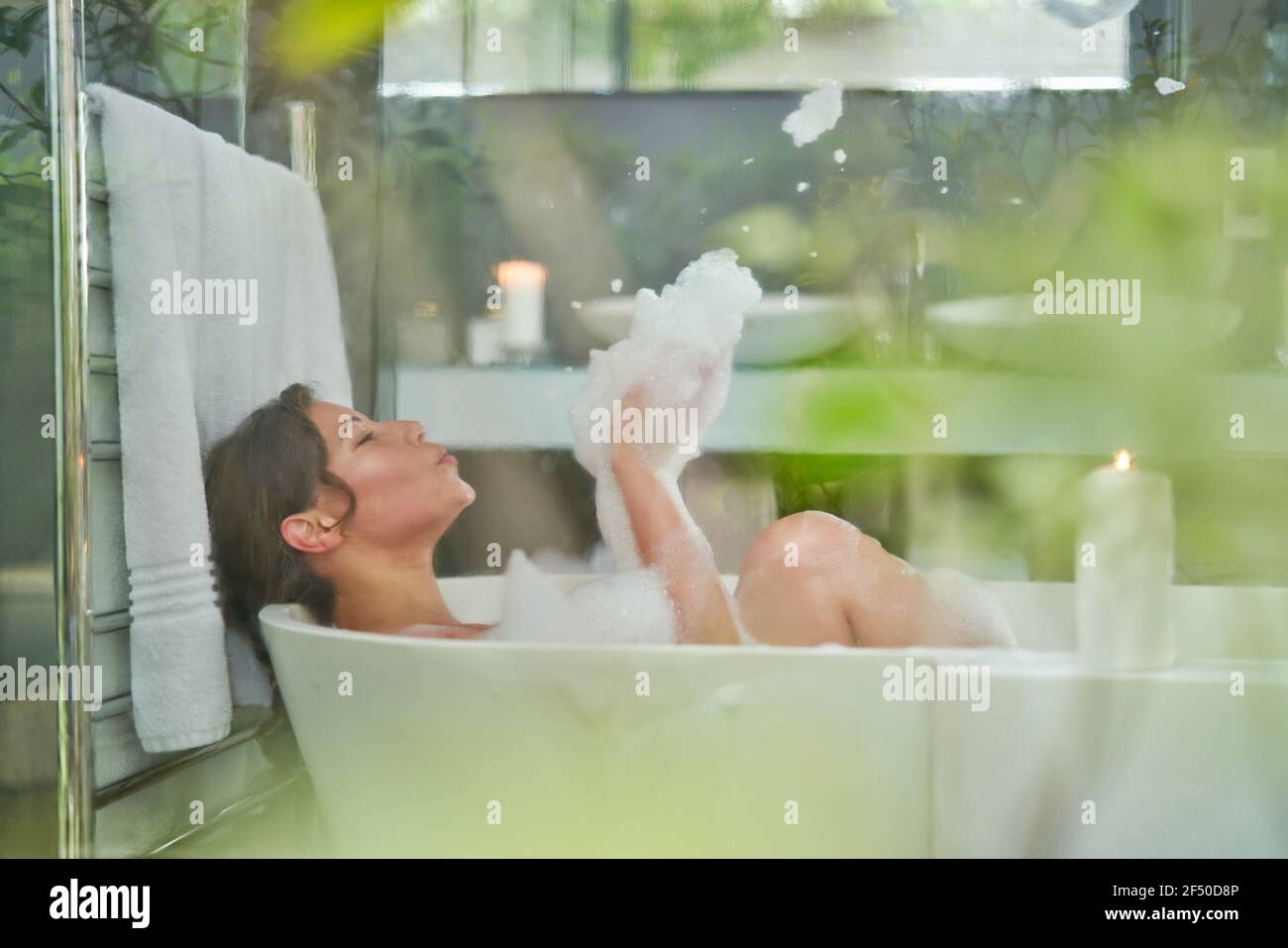 Verspielte Frau in Schaumbad in Luxus-Badewanne in Badezimmer Stockfoto