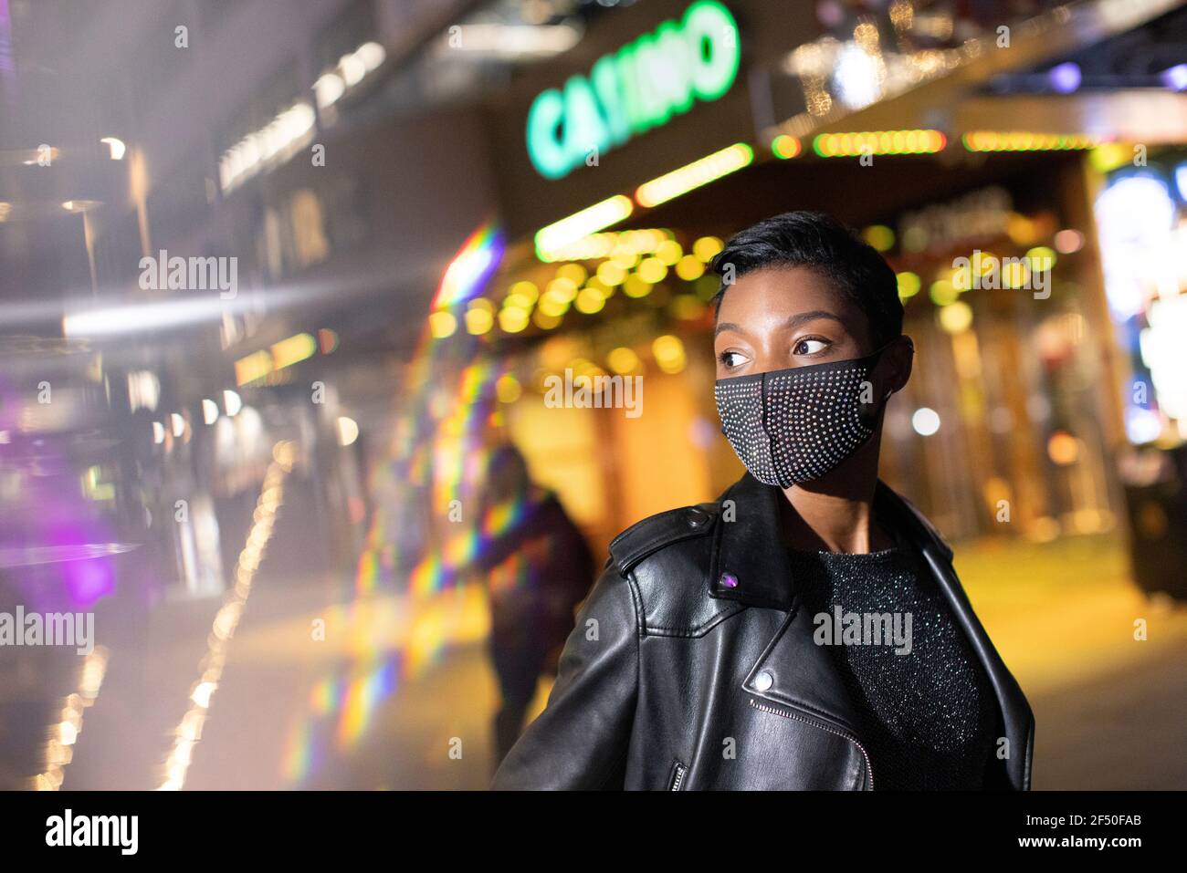 Junge Frau in besetzt Gesichtsmaske auf Stadt Straße an Nacht Stockfoto