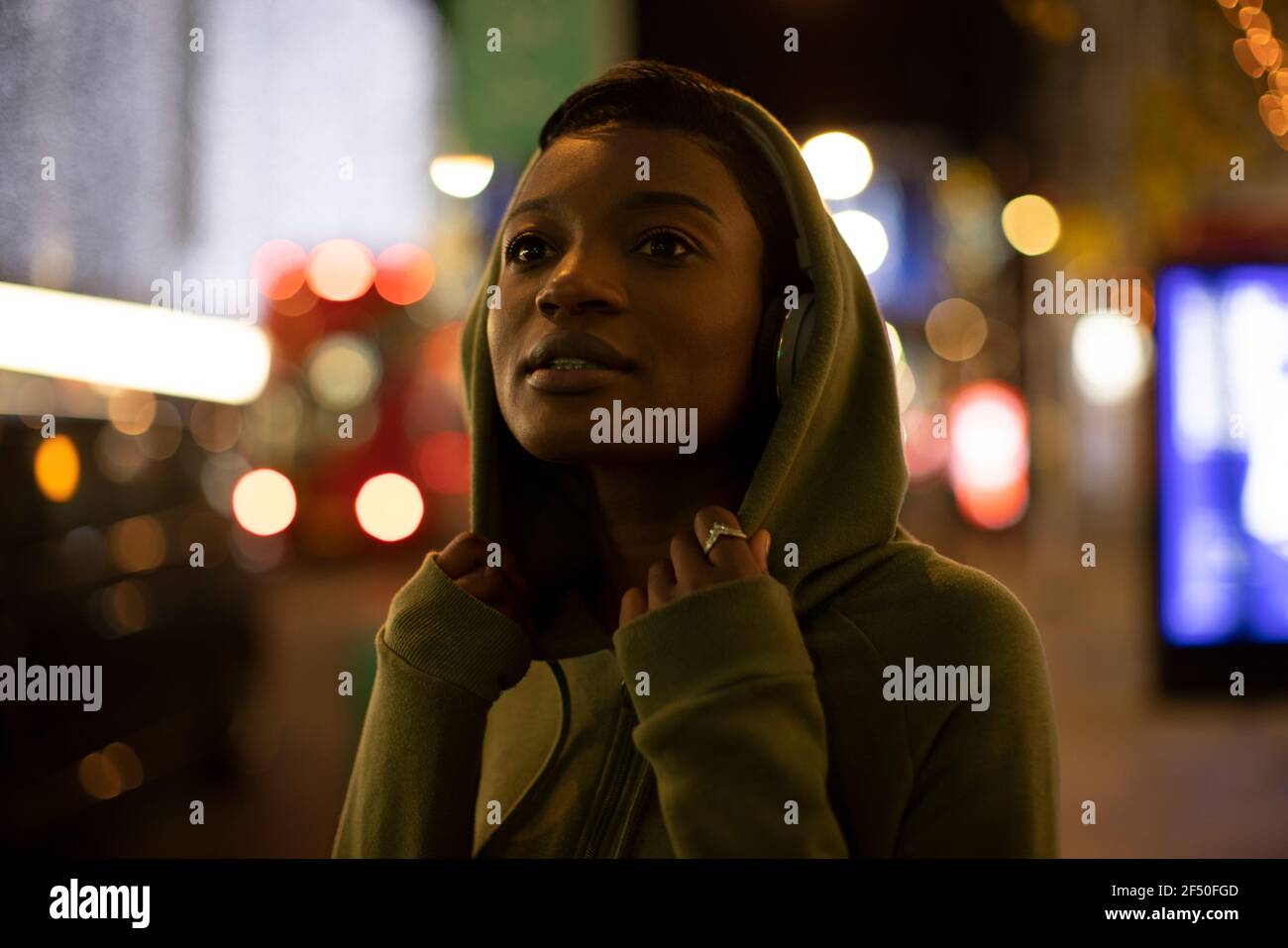 Junge Frau im Kapuzenpullover auf dem Bürgersteig der Stadt in der Nacht Stockfoto