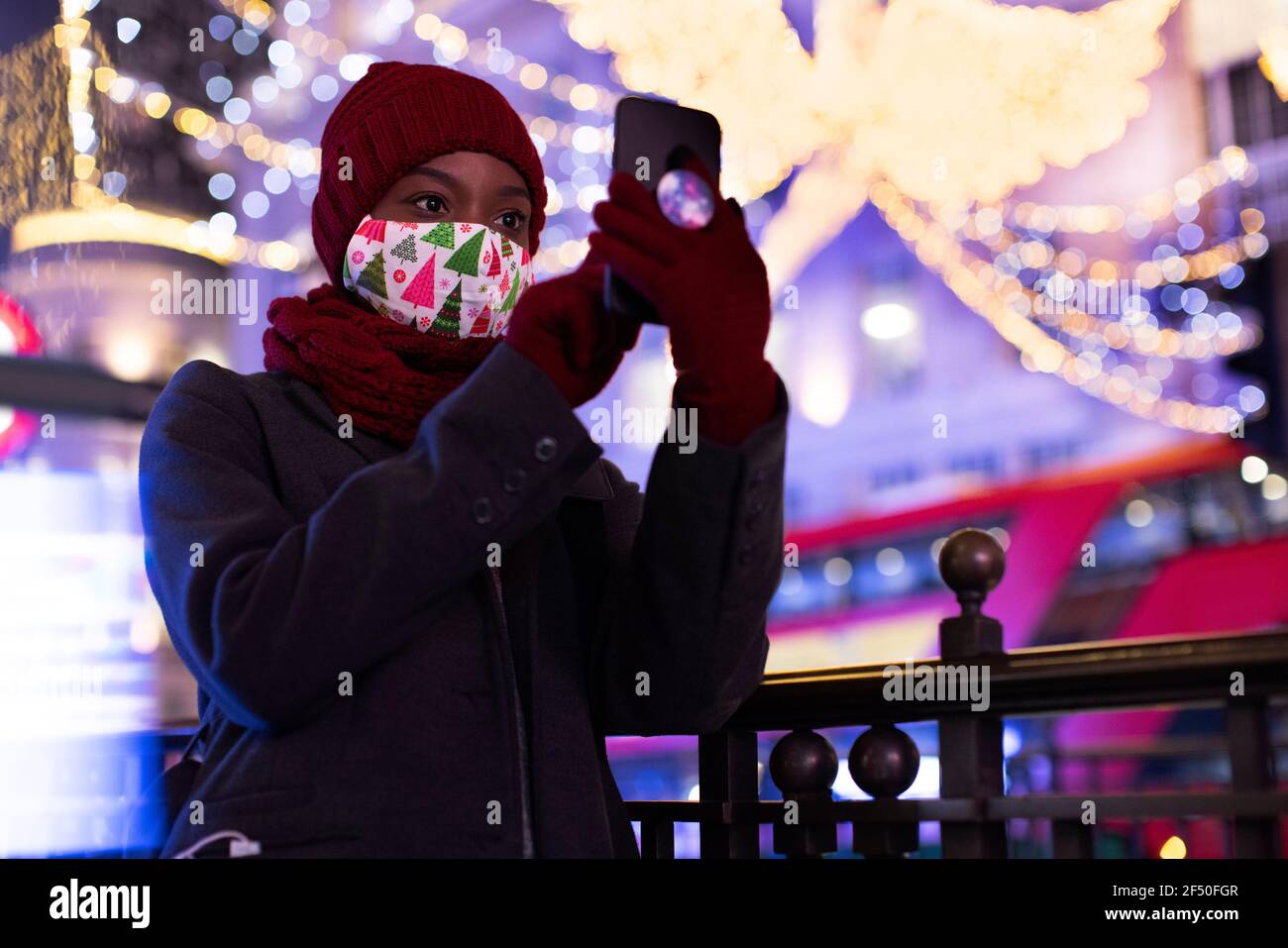 Junge Frau in Weihnachtsmaske unter Selfie zwischen den Lichtern der Stadt Nachts Stockfoto