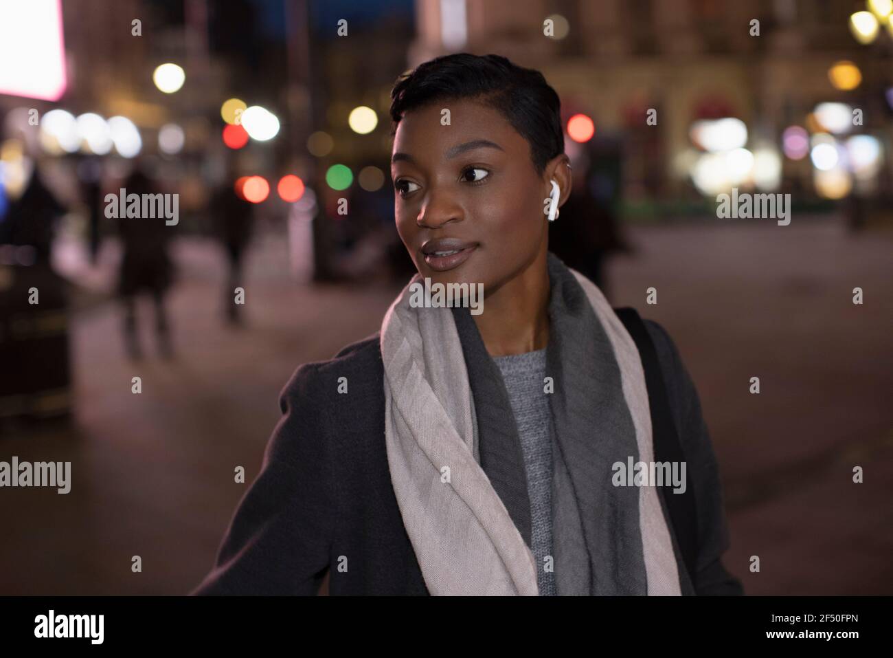 Junge Frau mit Ohrhörern in der Stadt Straße in der Nacht Stockfoto