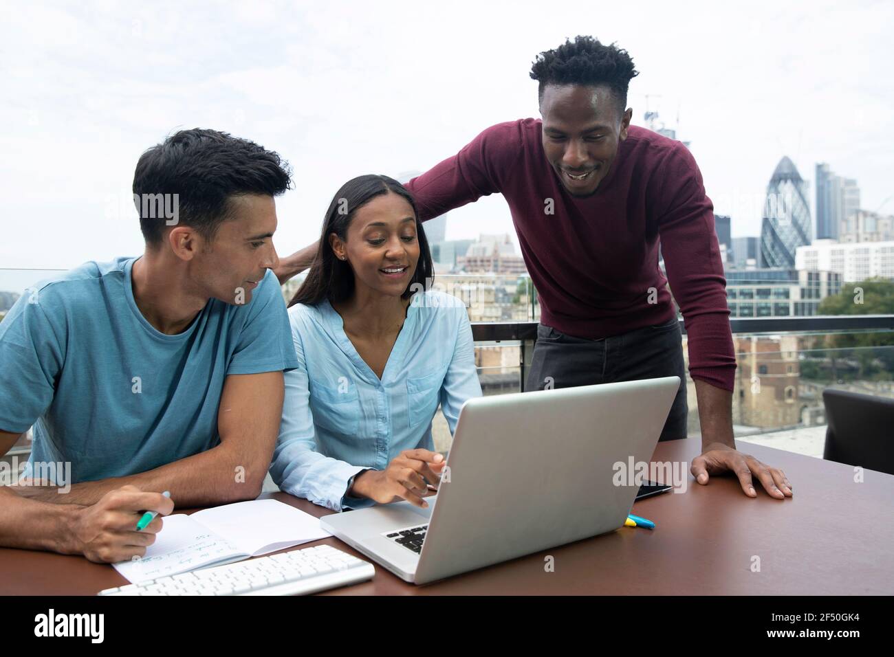 Geschäftsleute treffen sich am Laptop auf dem städtischen Balkon, London, Großbritannien Stockfoto