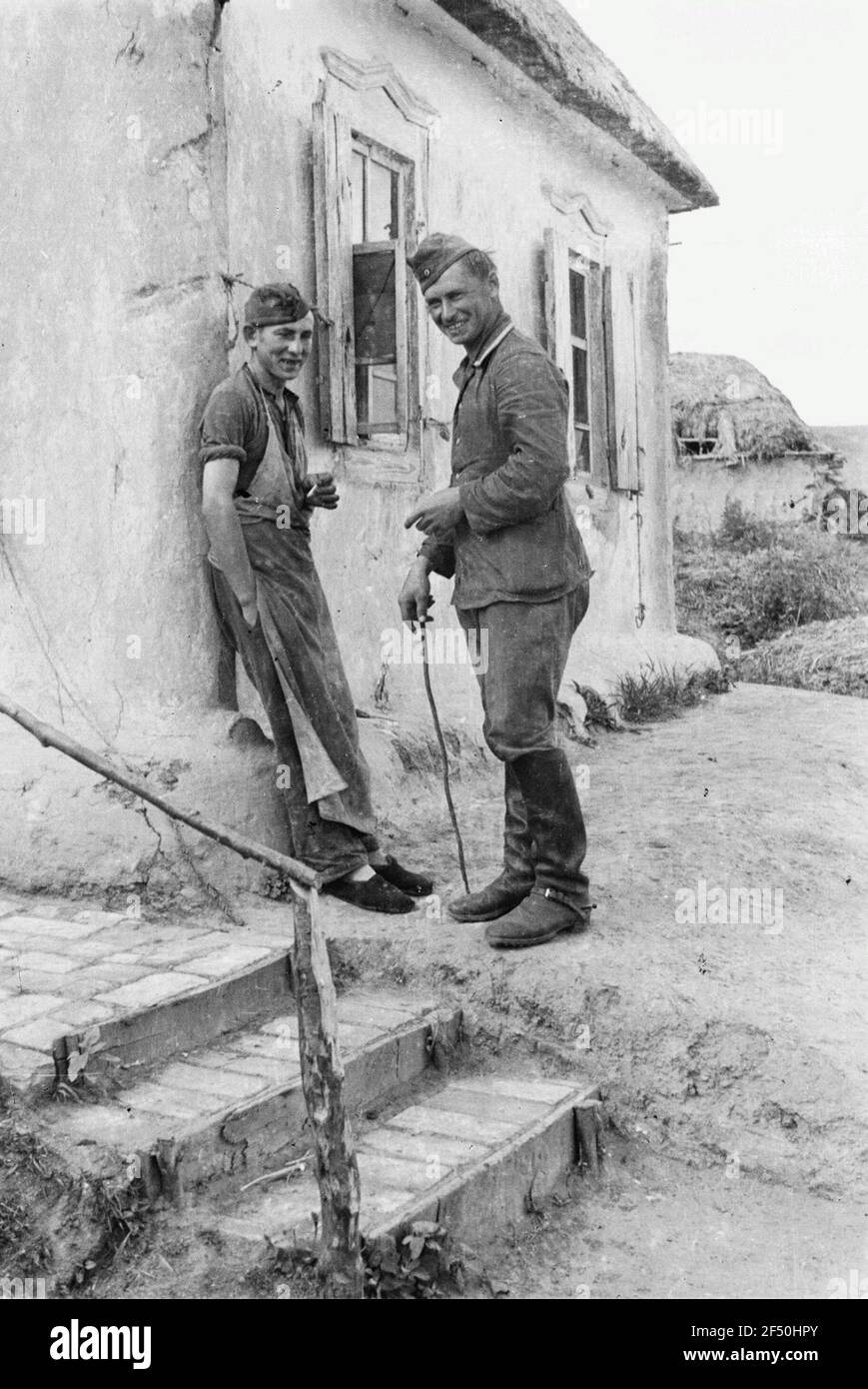 Zweiter Weltkrieg. Bilder auf der Vorderseite. Zwei Männer rauchen (vielleicht ein Einheimischer mit deutscher Militärmütze, rechts ein Wehrmachiger) Stockfoto