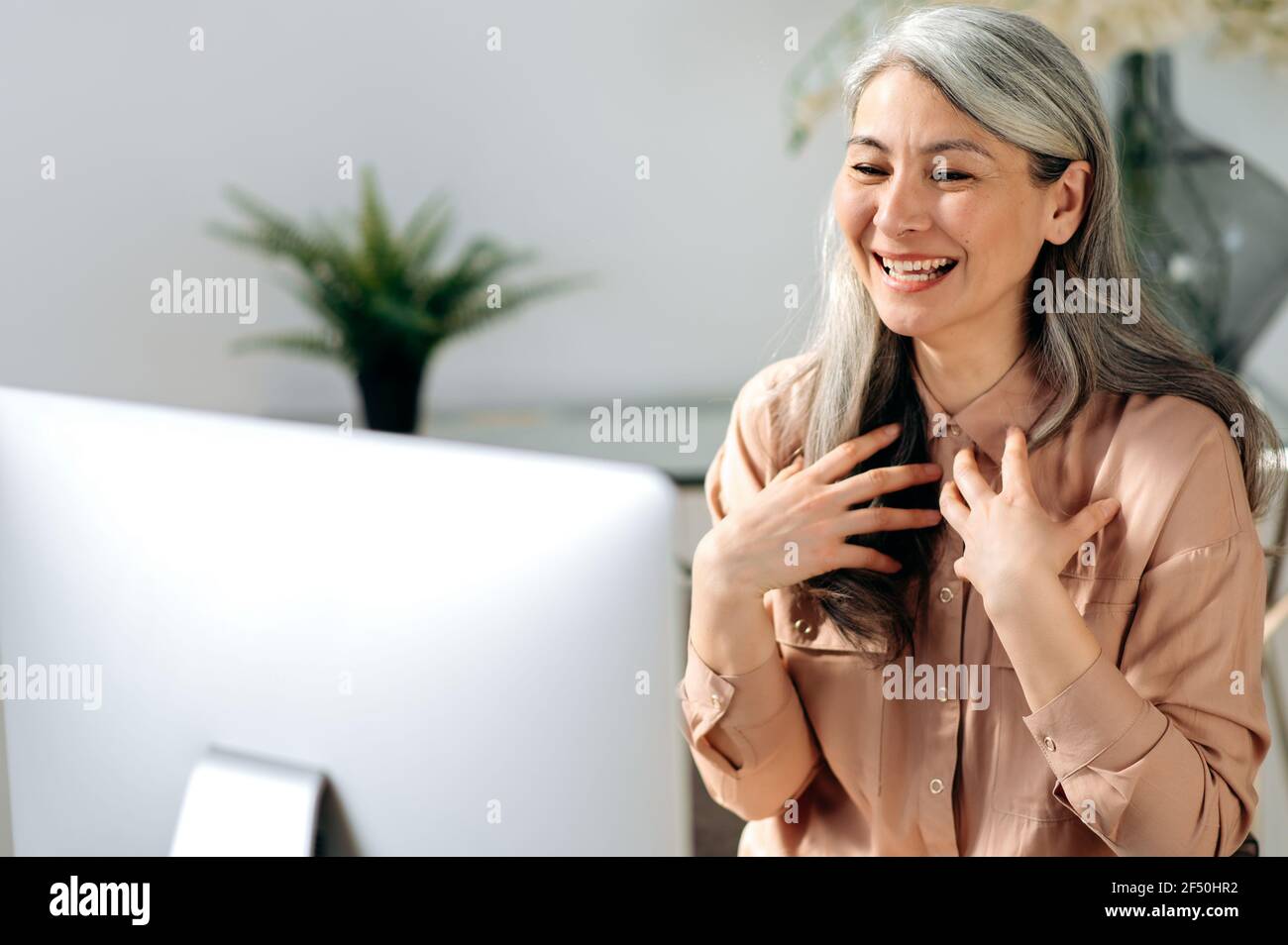 Selbstbewusste, erfolgreiche, schöne asiatische Frau, Managerin oder geschäftsführerin, die von zu Hause aus arbeitet, per Videokonferenz mit Mitarbeitern oder Freunden chattet, online trifft, mit den Händen gestikelt und freundlich lächelt Stockfoto