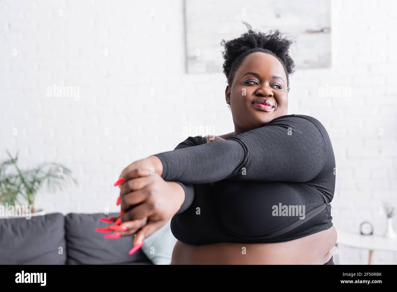 Zufrieden african american Übergewicht Frau in Sportbekleidung Ausübung zu Hause Stockfoto