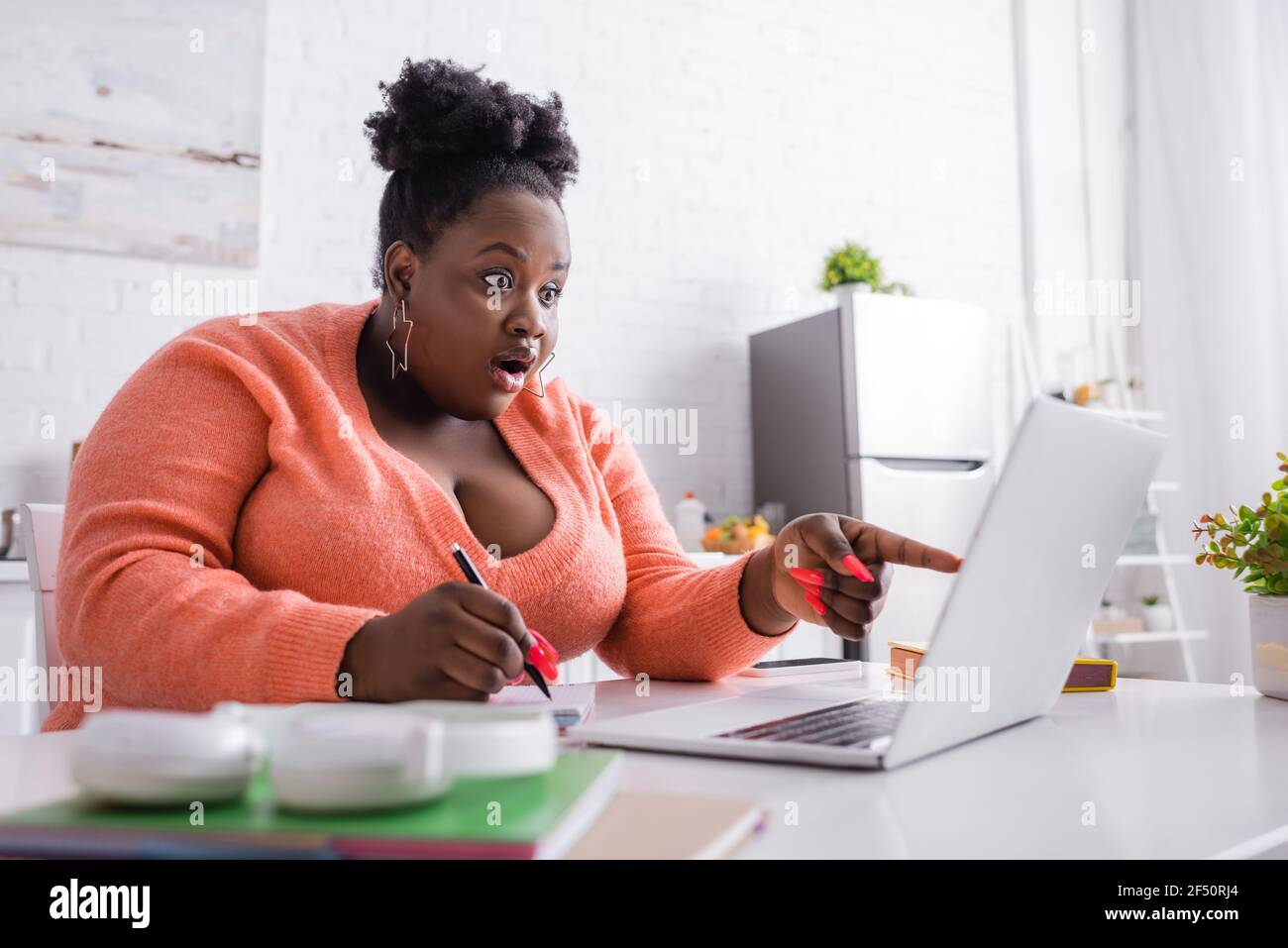 Schockiert afroamerikanischen plus size Freelancer zeigt mit dem Finger auf Notebook Stockfoto
