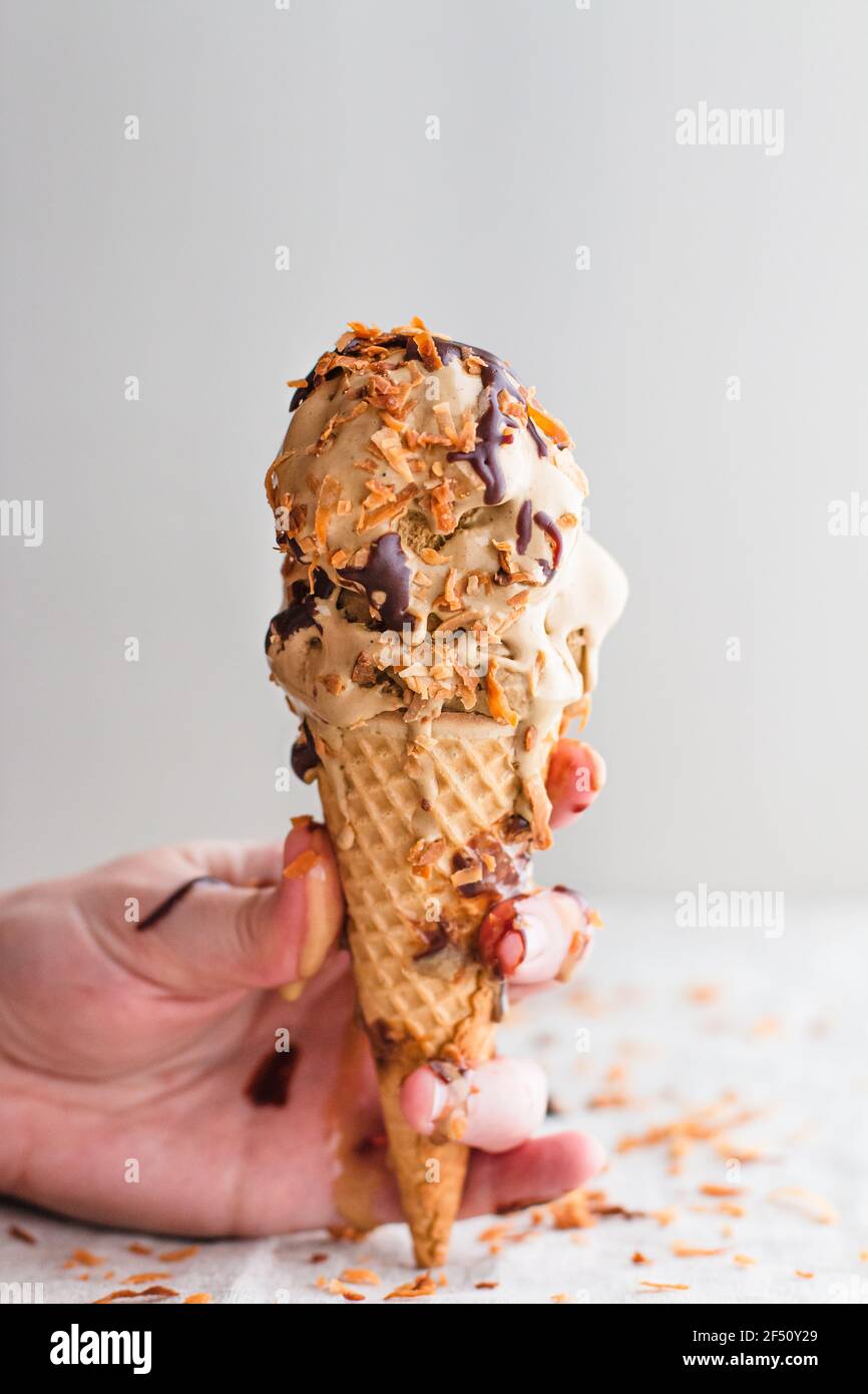 Hand hält eine Waffel Eis Kegel mit schmelzendem Eis gekrönt. Stockfoto