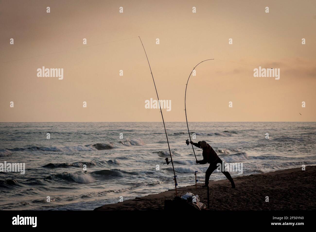 Ein Mann wirft seine Angelrute am Strand von el Prat de Llobregat, Barcelona. Stockfoto