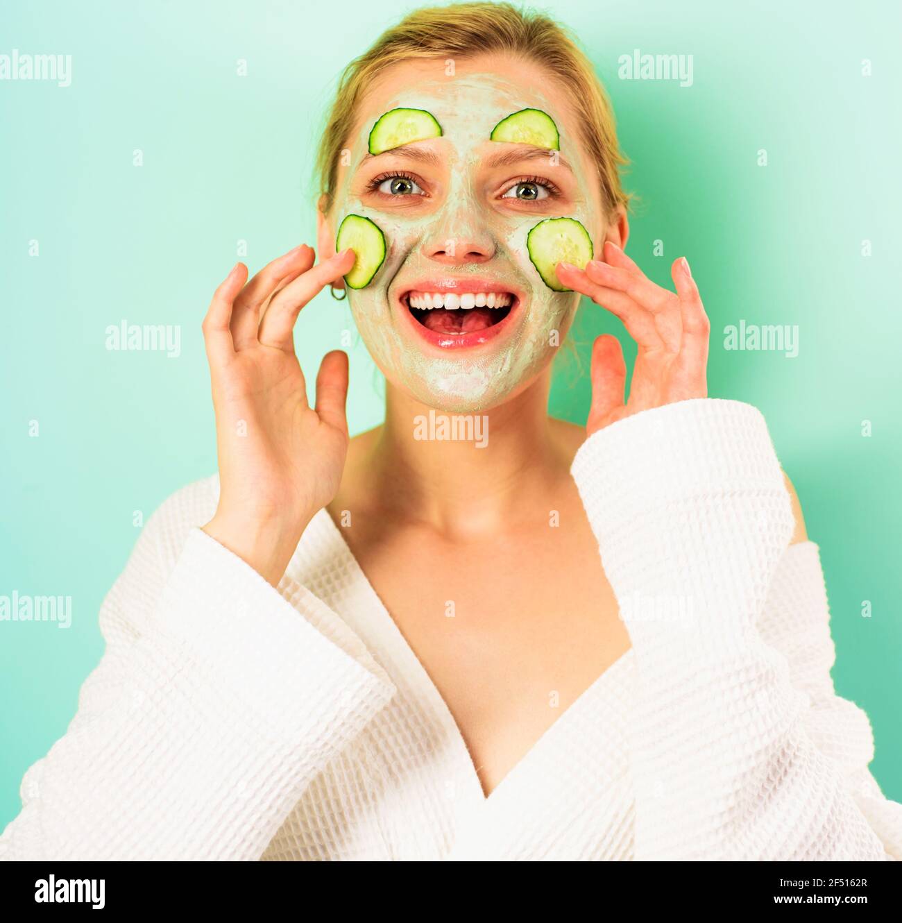 Lächelnde Frau mit kosmetischer Maske im Gesicht. Glückliches Mädchen mit Gesichtsmaske. Schönheitsbehandlung. Spa-Therapie. Kosmetische Verfahren. Stockfoto