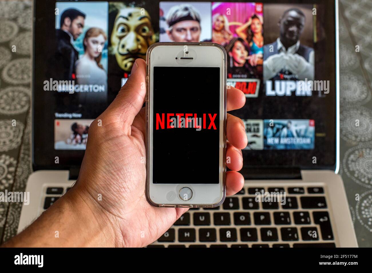 In dieser Abbildung wird die Netflix-App auf einem Smartphone-Bildschirm und eine Netflix-Website auf einem Laptop im Hintergrund angezeigt. Stockfoto