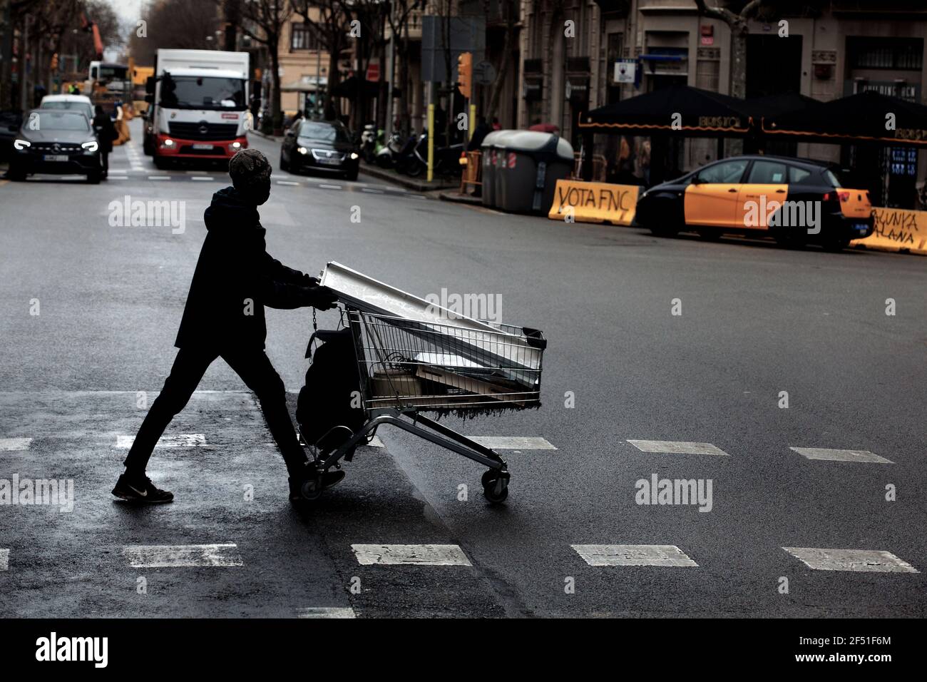 Afrikanischer Einwanderer, der einen Trolley aus Schrott schiebt, Barcelona, Spanien. Stockfoto