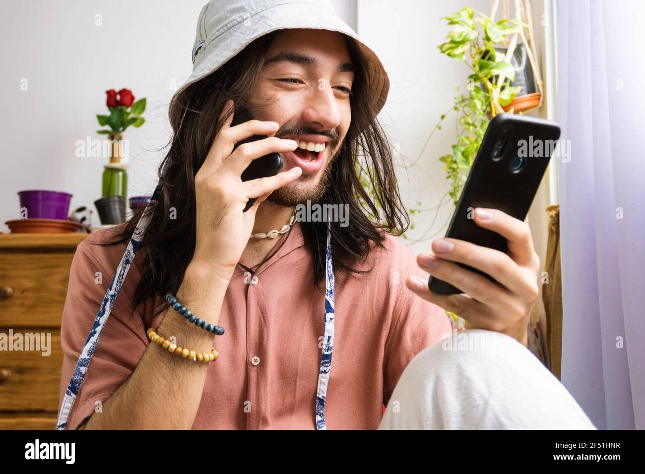 Freelancer Hipster Mann im Gespräch auf zwei Smartphones, junger Mann Multitasking, Kleidung Stylisten Job, mit einem Eimer Hut. Stockfoto