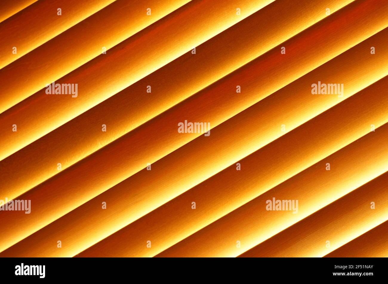 Holzjalousien im Fenster - schräge Aussicht. Fenstervorhänge aus Naturholz. Schräge orangefarbene Linien. Jalousien in Nahaufnahme. Stockfoto