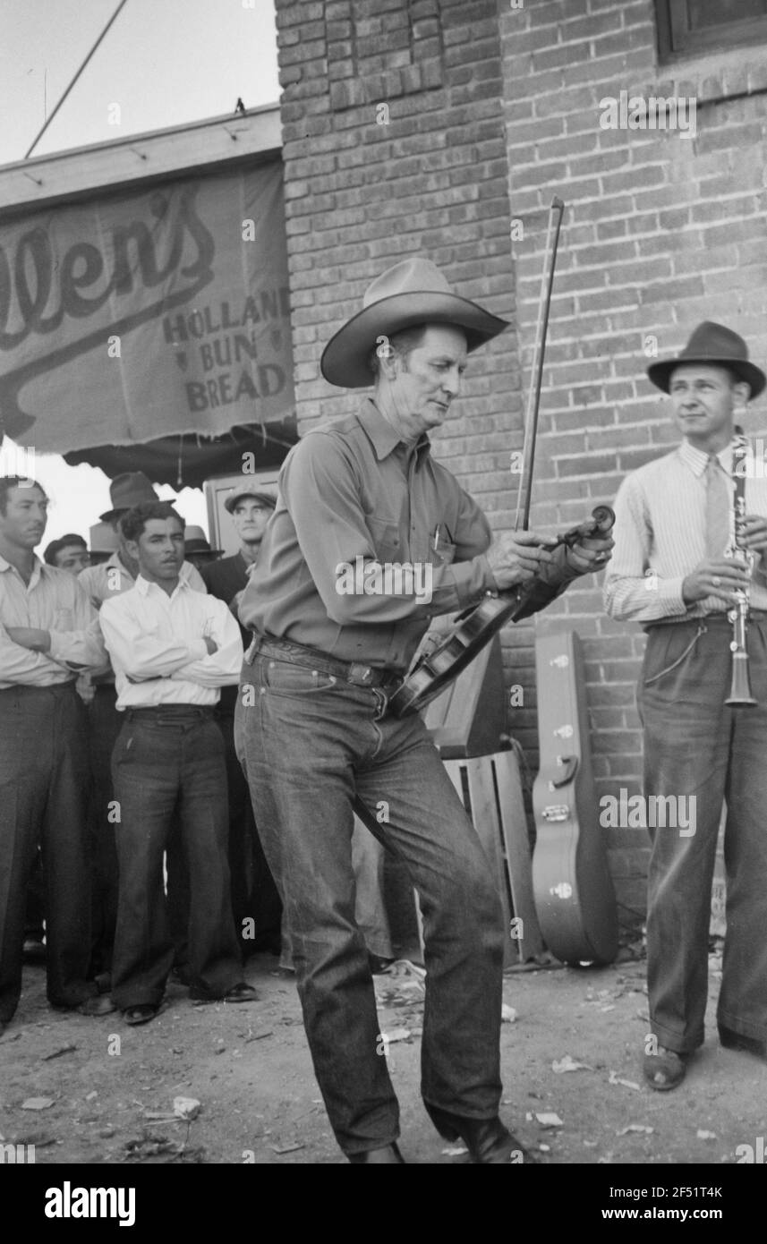 Mitglied des Orchesters, das am Samstagnachmittag außerhalb des Lebensmittelladens spielt und seine Geige stimmt, Phoenix, Arizona - 1940 Stockfoto