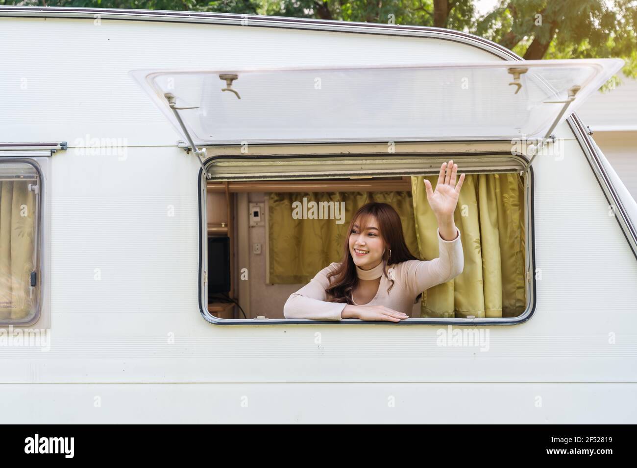 Glückliche junge Frau, die ihre Hand am Fenster eines hebt Wohnmobil Wohnmobil Wohnmobil Stockfoto