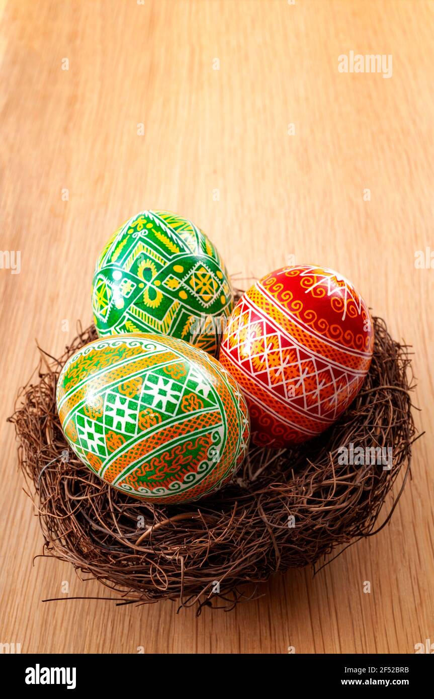 Osterferien und Frühlingsfest Konzept mit drei ostereiern mit einem komplexen Muster in einem Vogelnest isoliert auf einem Holzhintergrund wi dekoriert Stockfoto
